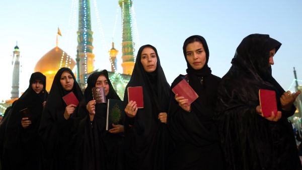 Iranian women hold their ID as they wait in line to cast their votes for municipal and presidential elections at a polling station at the Massoumeh shrine in the holy city of Qom, 130 kms south of Tehran, on May 19, 2017. (AFP/Ali Shaigan)
