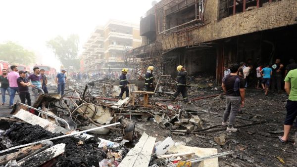 Iraqis, including firefighters, gather at the site of a suicide car bombing claimed by the Islamic State group on July 3, 2016 in Baghdad's central Karrada district. (AFP/Sabah Arar)