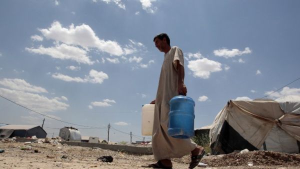 Abu Shiab carries water on May 31, 2016 at the Alexanzan camp in the Dora neighburhood outside of Baghdad where he is taking shelter with his family after they were displaced from the Jbeil, a village near Fallujah due to clashes between pro-government forces and Daesh. (AFP/Sabah Arar)