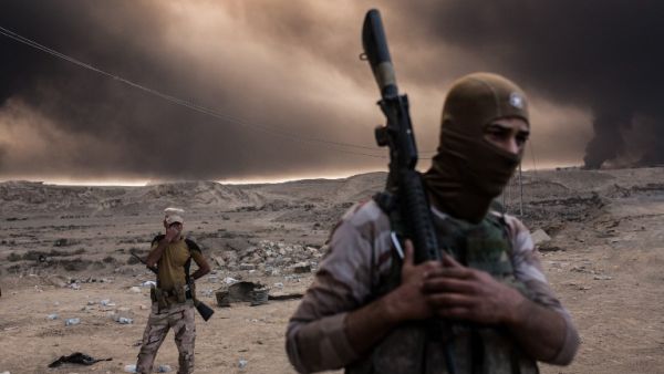 Iraqi soldiers look on as smoke rises from the Qayyarah area, some 35 miles south of Mosul, on October 19, 2016, as Iraqi forces take part in an operation against Daesh to retake the main city. (AFP/Yasin Akgul)