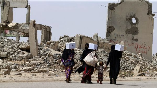 Iraqi women walk past destroyed buildings south of Mosul on May 26, 2017, as government forces continue their offensive to retake the city of Mosul from Islamic State (IS) group fighters. (Karim Sahib/AFP)