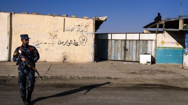 An Iraqi policeman stands guard as the Iraqi army search for booby-trapped buildings in eastern Mosul on 16 January. (AFP/File)