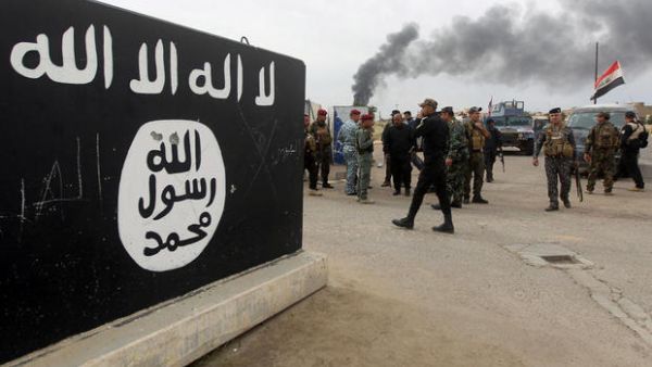 Iraqi security forces and Shiite fighters from the Popular Mobilisation units gather next to a mural depicting the emblem of the Daesh in Tikrit, on 1 April 2015. (AFP/File)