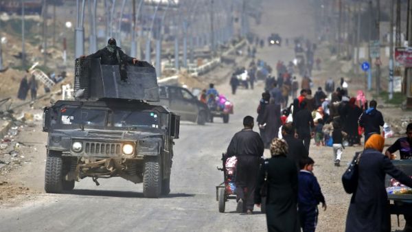 Iraqi security forces drive past civilians fleeing their homes in Mosul's old city on March 30, 2017, due to the ongoing battles between government forces and Daesh fighters. (AFP/Ahmad Gharabli)