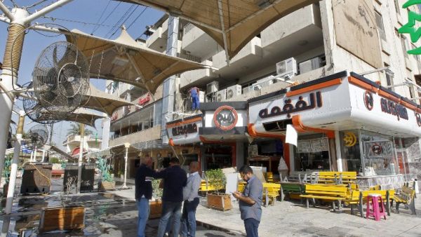 Iraqis check an ice cream shop in Baghdad's Karrada district in the aftermath of a car bom explosion on May 30, 2017. (Sabah Arar/AFP)