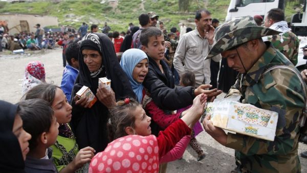 Displaced Iraqis who fled Mosul's Old City receive food as they arrive in the Al-Tayaran neighbourhood on April 8, 2017. (AFP/Ahmad Gharabli)