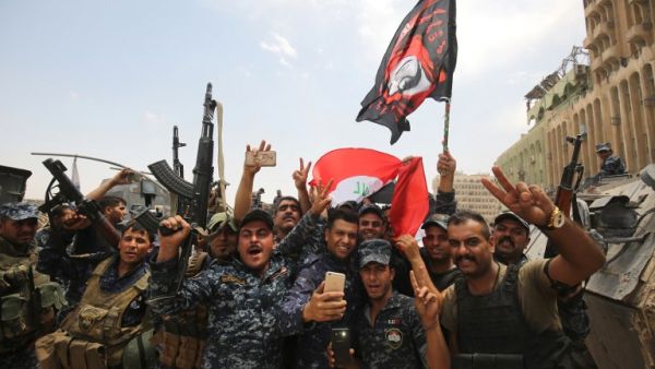 Members of the Iraqi federal police dance and wave their country's national flag in celebration in the Old City of Mosul on July 8, 2017 (Ahmad Al-Rubaye/ AFP)