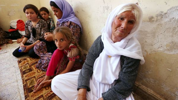 An Iraqi Yazidi family that fled violence in the northern Iraqi town of Sinjar sits at a school. [AFP]