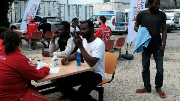 Migrants speak with members of the Italian Red Cross who help them to contact their family on March 6, 2017. (AFP/Alberto Pizzoli)
