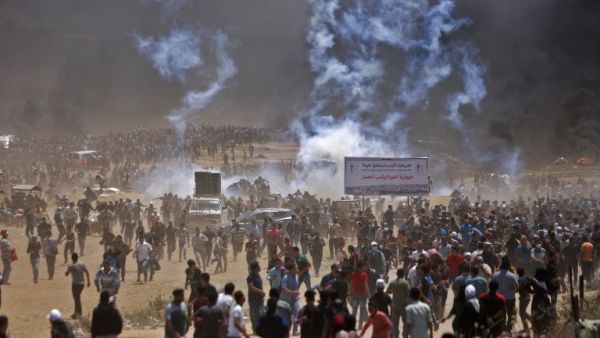 Palestinians run for cover from tear gas during clashes with Israeli security forces near the border between Israel and the Gaza Strip, east of Jabalia/AFP
