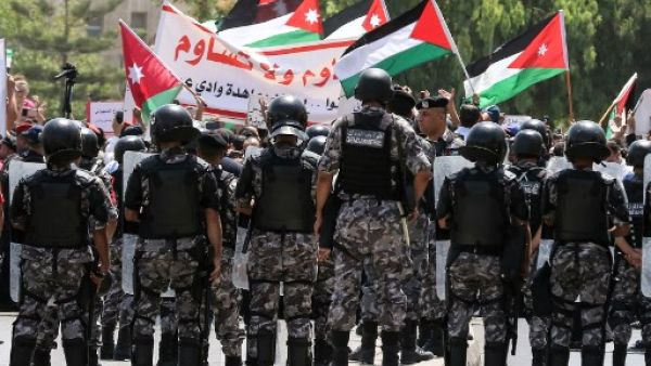 AFP - Jordanian security forces stand on guard before protesters as they wave national flags and chant slogans during a demonstration in the capital Amman on July 28, 2017.
