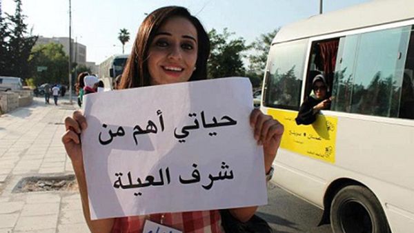 A young Jordanian woman holds a placard that reads, "My life is more important than family honor." (File photo)