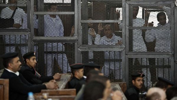 Journalists stand in the defendants' cage in a 2014 trial in Egypt. (AFP/File)