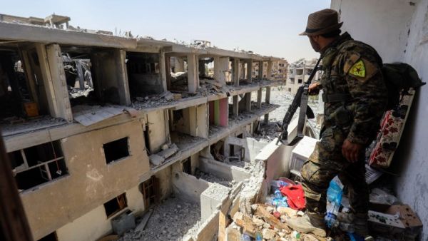 A member of the Kurdish People's Protection Units (YPG), which Ankara deems to be a terror group, moves through destroyed buildings in Raqa on July 28, 2017 (AFP)