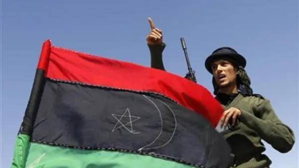 مقاتل من المعارضة يحمل العلم الليبي الجديد القديم
