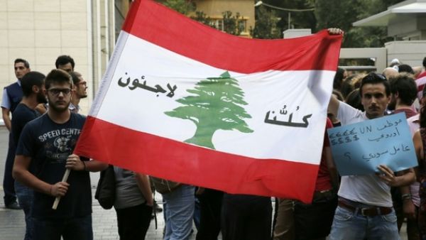 Lebanese protesters hold a Lebanese national flag on which is written in Arabic, "We are all refugees" on July 18, 2016 in the capital Beirut. (AFP/Joseph Eid) Lebanese protesters hold a Lebanese national flag on which is written in Arabic, "We are all refugees" on July 18, 2016 in the capital Beirut. (AFP/Joseph Eid)