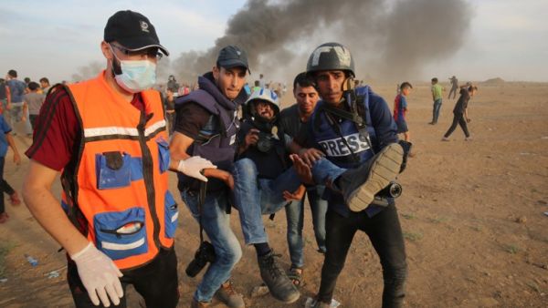 Palestinian paramedics and journalists carry a wounded fellow journalist during clashes with Israeli forces east of Gaza city. (Said KHATIB / AFP)