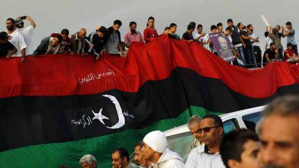 Libyans hold a large version of their national flag during a demonstration. (AFP Photo / Abdullah Doma)