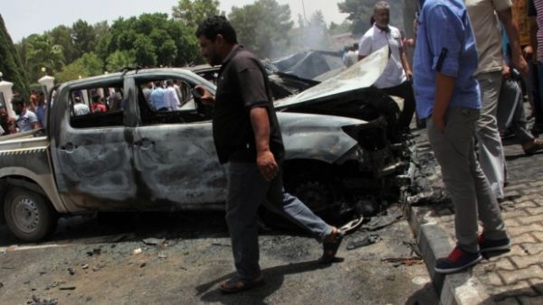 Men check the site of an explosion outside parliament's local building in al-Baida on 26 June. (AFP/File)