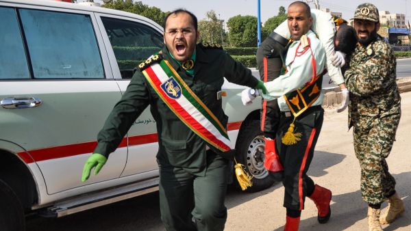 This picture taken on September 22, 2018 in the southwestern Iranian city of Ahvaz shows an Iranian soldier carrying an ijured comrade at the scene of an attack on a military parade that was marking the anniversary of the outbreak of its devastating 1980-1988 war with Saddam Hussein's Iraq (AFP)