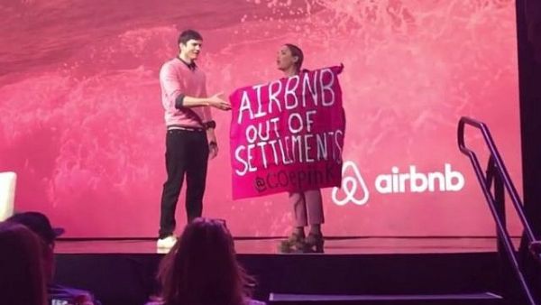 A protester against Airbnb's listing of West Bank settlement rentals during an interview with Ashton Kutcher at Airbnb Open in Los Angeles in 2016. (Screenshot/YouTube)