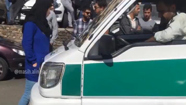 Screenshot from the video shows the woman while standing in the face of the morality police van to disrupt them while arresting  women over improper hijabs. (Socialmedia)