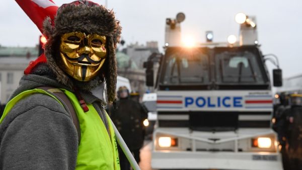 A masked protestor stands in front of a police vehicle in Paris on January 5, 2019, during a rally by yellow vest "Gilets Jaunes" anti-government protestors. (Bertrand GUAY / AFP)