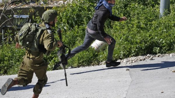 An Israeli soldier chases a Palestinian protester during clashes following a demonstration against Jewish settlements west of Ramallah, on March 8, 2019. (ABBAS MOMANI / AFP)