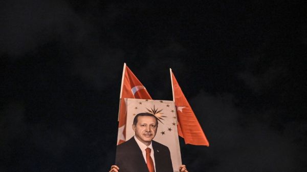 A supporter of Justice and development party (AKP) holds a banner picturing Turkish president Recep Tayyip Erdogan during a rally near the headquarters of the conservative AKP party on March 31, 2019. (AFP)