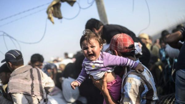 A man carries his child across the border (BULENT KILIC/AFP)
