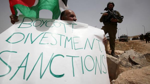 A Palestinian holds a placard as part of a protest during which they try to set up a tent on 8 June, 2013 near the Jewish settlement of Bat Ayin and the West Bank village of Surif, west of Hebron. (AFP/File)