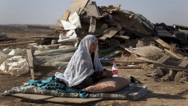 A Bedouin woman sits in front of a razed home. (AFP/File)