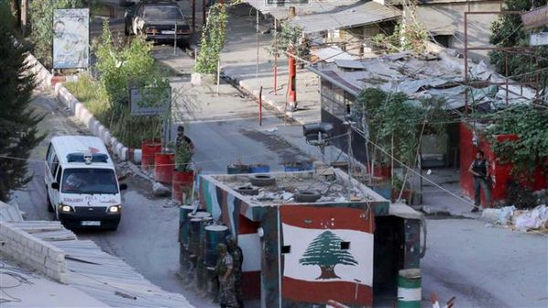 Members of the Palestinian Fatah movement and Lebanese army soldiers watch as an ambulance evacuates the wounded from Ain al-Hilweh refugee camp near Lebanon’s southern port city of Sidon during clashes on August 25, 2015. (AFP/File)