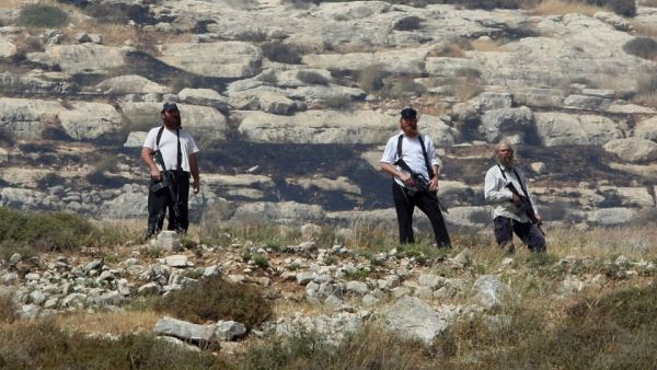 Armed settlers overlook a Palestinian village south of Nablus during confrontations following the setting on fire of Palestinian-owned fields on Jan. 1, 2010. (AFP/Jaafar Ashtiyeh)
