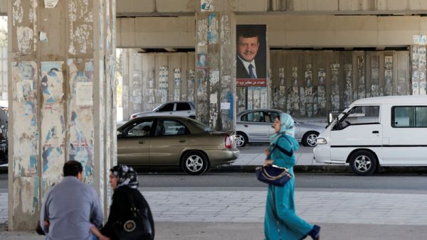 A woman walks past a poster of Jordan's King Abdullah. (AFP/File)
