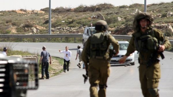 Israeli soldiers are seen close to settlers who are attacking a photographer's car, near illegal settlement of Beit El. (AFP/File)