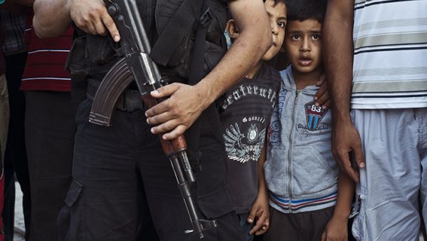 Palestinian boys watch as Hamas militants parade in Shejaiya, Gaza, following the brutal conflict with Israel in 2014. The highest levels of extremism are in countries experiencing ongoing conflicts, where children are particularly vulnerable to recruitment. (AFP/Roberto Schmidt)