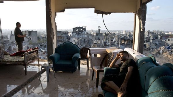 Two young men sit among the aftermath of brutal Israeli offensive on Gaza. (AFP/Roberto Schmidt)