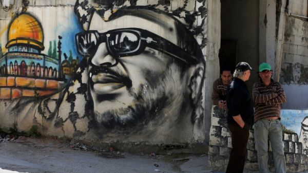 Palestinian refugees stand next to graffiti bearing a portrait of late Palestinian President Yasser Arafat at the Ain Al-Helweh refugee camp. (AFP/File) Palestinian refugees stand next to graffiti bearing a portrait of late Palestinian President Yasser Arafat at the Ain Al-Helweh refugee camp. (AFP/File)