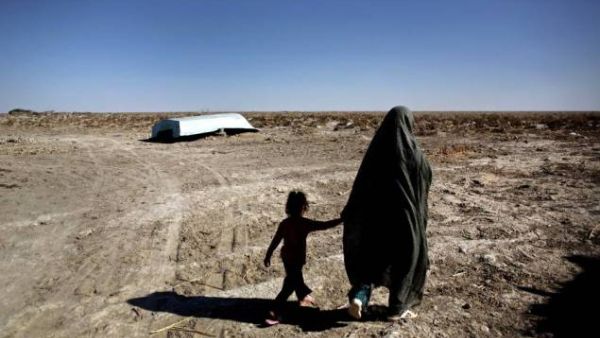 An Iranian woman and her daughter walk past an abandoned boat in the village of Sikh Sar. (AFP/File)