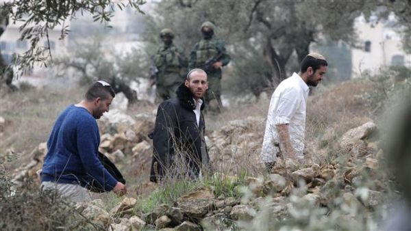 Israeli settlers walk past Israeli soldiers, who are searching Palestinian homes in the occupied southern West Bank. (AFP/File)