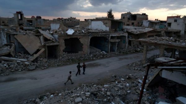 Syrian children walk past heavily damaged buildings in the rebel-held town of Douma, on the eastern edges of Damascus on February 27, 2016. (AFP/Sameer Al-Doumy)