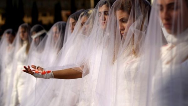 Activists from NGO Abaad dressed as brides and wearing injury patches, protest in downtown Beirut on 6 December 2016. (AFP/File)