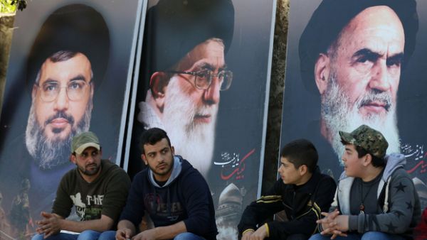 Young Lebanese sit below posters of Shia leaders including Hezbollah's Hassan Nasrallah. (AFP/File)