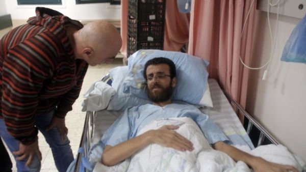 Mohammed al-Qiq, a Palestinian prisoner on hunger strike, talks to a man in a hospital in the northern Israeli town of Afula on February 5, 2016. (Ahmad Gharabli/AFP)