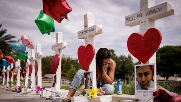 A woman writes a note on a cross at a memorial for each of the 49 victims of the Pulse Nightclub, next to the Orlando Regional Medical Center, June 17, 2016 in Orlando, Florida. (AFP/Drew Angerer)