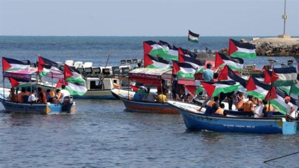 Palestinians hold their national flag as they ride boats during a rally to show support for activists aboard a flotilla of boats who are soon to set sail for Gaza in a fresh bid to break Israel's blockade, at the seaport of Gaza on June 24, 2015. (AFP/File)