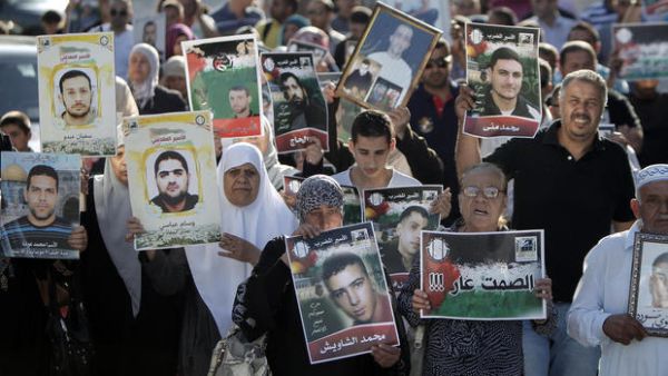 Palestinians hold posters with slogans and portraits of detainees during a demonstration on 10 June, 2014 outside the Red Cross building in Jerusalem in support of Palestinian prisoners who have been on hunger strike for six weeks. (AFP/File)