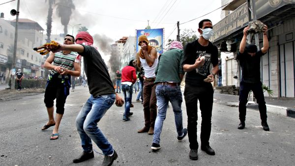 Palestinian youth throw rocks at Israeli troops in protest. (AFP/Hazem Bader)