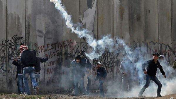 Palestinians throw rocks as Israeli occupation forces shoot teargas in Qalandia. (AFP/File)